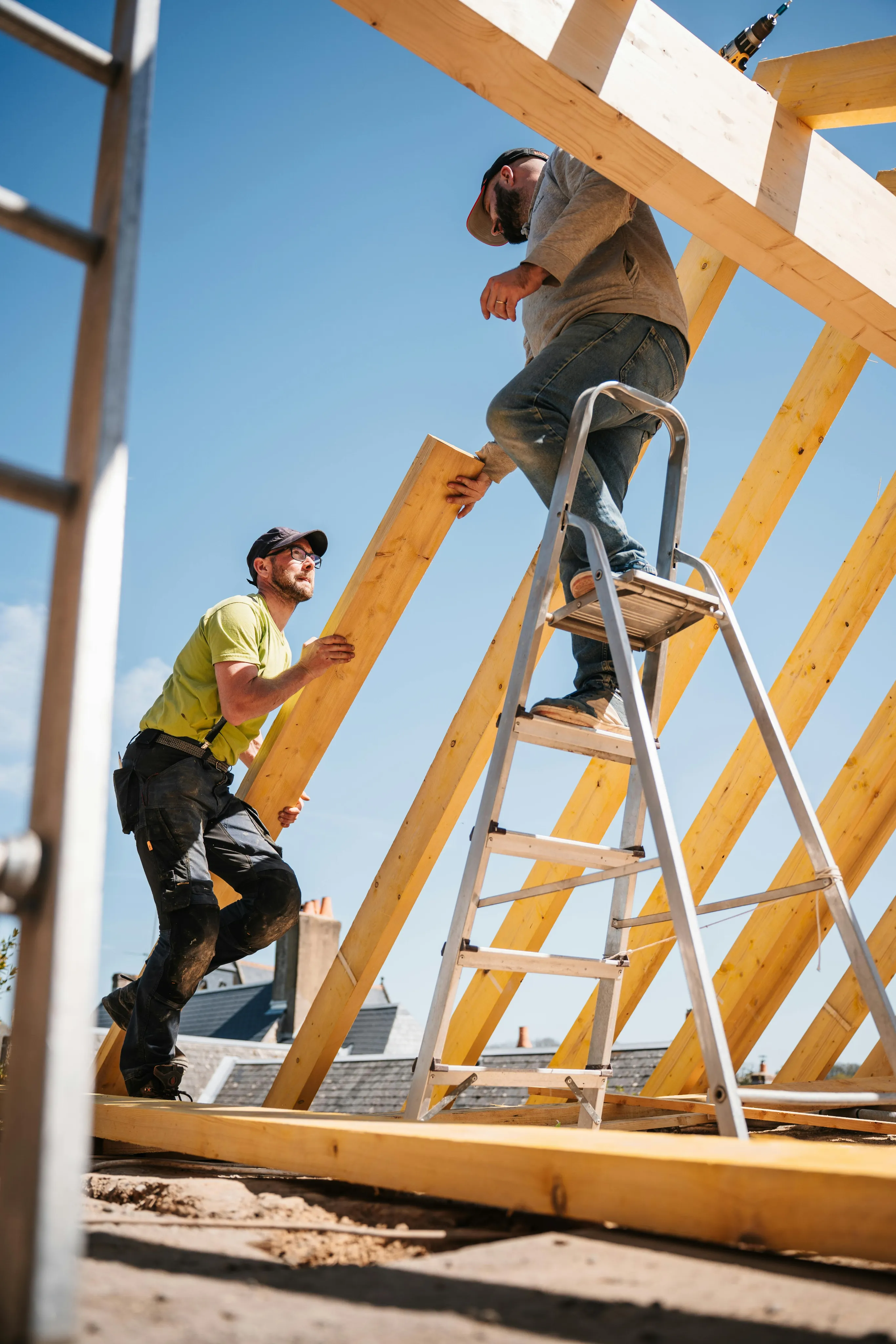 Workers framing a roof structure on a ladder